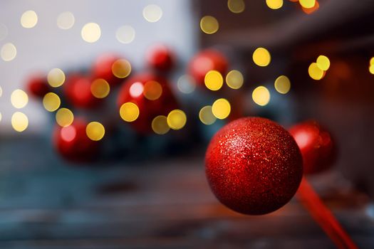 Christmas red glitter ball on blurred background. Holiday ornaments. Card with New Year decoration and copy space for congratulations.