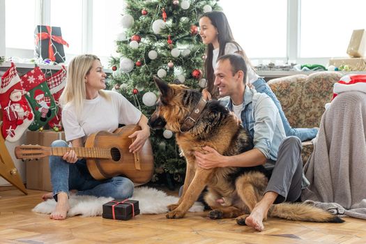 happy family and cute dog having fun at christmas tree. atmospheric emotional moments. merry christmas and happy new year concept