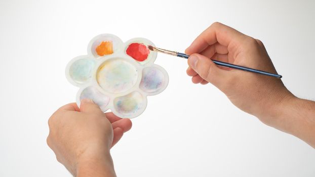 men's hands with palette and brush, gesture to mix paint. High quality photo