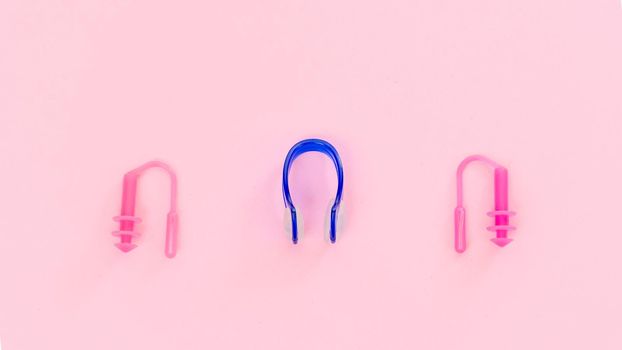 Swimmer set - earplugs and nose clip on pink background close-up. High quality photo