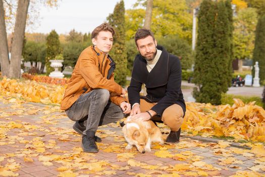 Father and son with a pet on a walk in the autumn park.