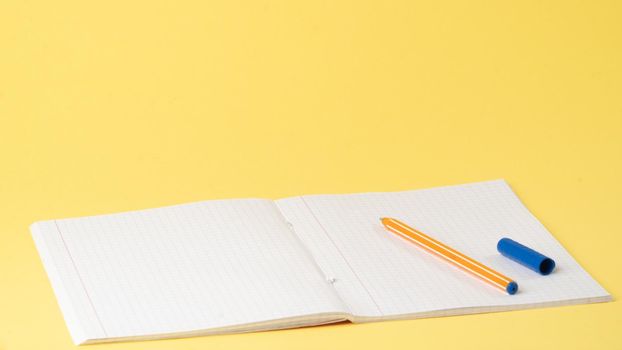 Notebook and pen on the table on a yellow background, space for text, learning. High quality photo