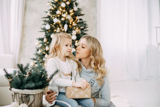 Happy family: mother and daughter. Family in a bright New Year's interior with a Christmas tree.