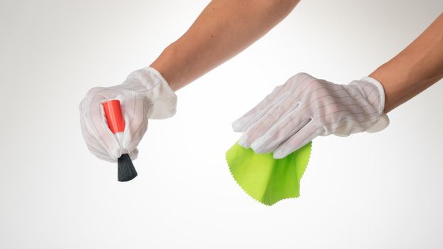 Hand gesture on a white background wearing protective gloves with a screen wipe cloth and dust brush. High quality photo