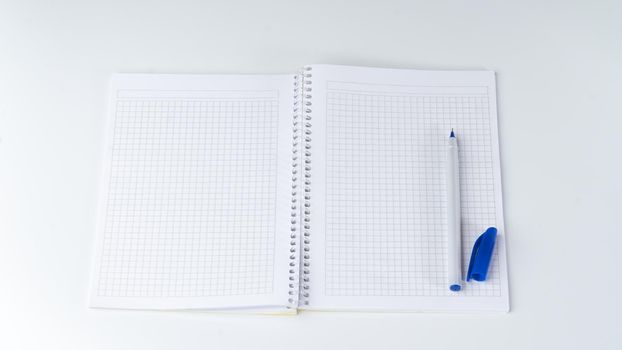 Open notebook in a cage, on the right side there is a pen with an open cap. High quality photo