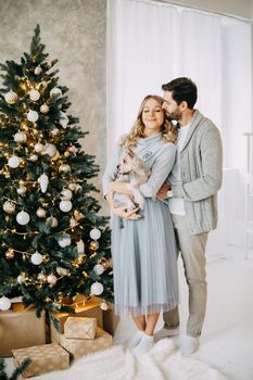 Happy family: mom, dad and pet. Family in a bright New Year's interior with a Christmas tree.