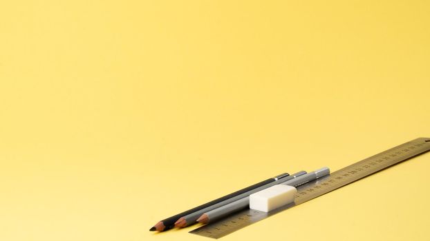 Simple pencils, ruler and eraser on a yellow background. High quality photo