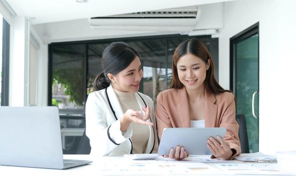 Two beautiful young asian businesswoman working together using digital tablet at office..