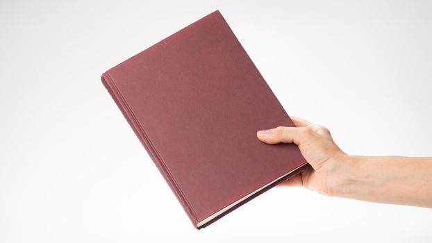 A woman's hand holds a closed book, there is room for an inscription on the cover. High quality photo