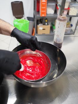 chef making for icing a red drip cake in the professional kitchen lab