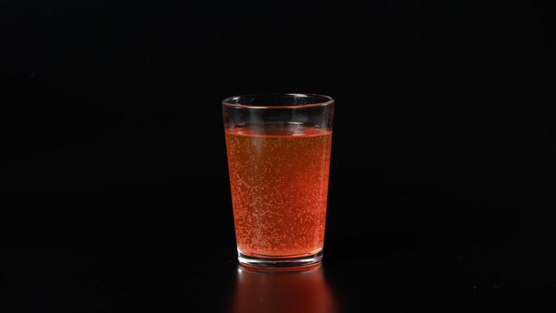 Glass with carbonated orange water on a black background, bubbles, drink, cocktail. High quality photo