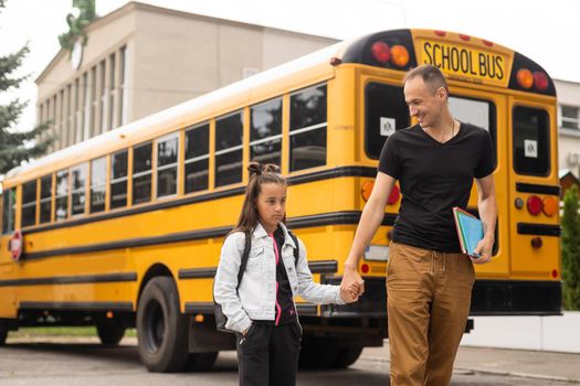 first day at school. father leads a little child school girl in first grade