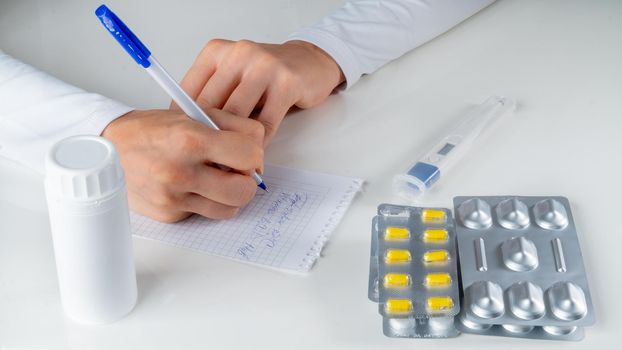 The doctor writes a medical prescription for the disease against the background of drugs, tablets. High quality photo