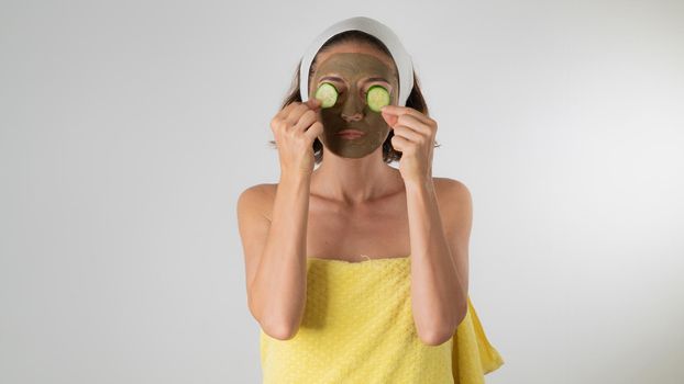 The woman makes a face mask and removes bags under the eyes with cucumber - self-care at home. High quality photo