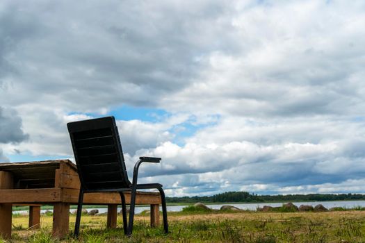 wooden deck chairs and chairs on the sandy beach of the lake against a cloudy sky. Summer beach holidays