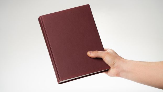 A man's right hand holds a book or notepad for writing. High quality photo