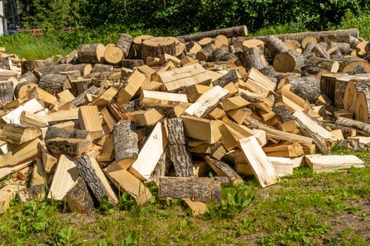 a pile of chopped wood in the yard of the house. preparation for winter. heating the house with a stove