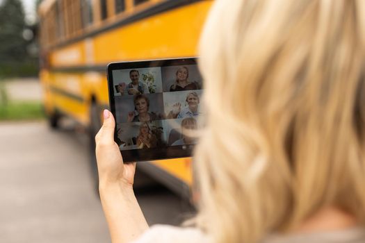 Female Teacher Or Student With Digital Tablet near the school bus. video chat.