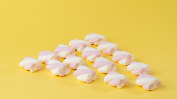 Marshmallows on a yellow background in the form of a triangle. High quality photo