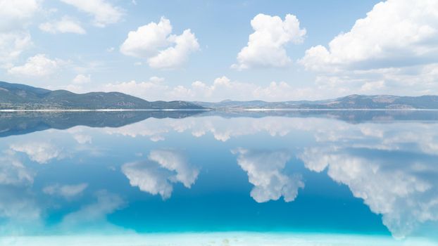 The sky and clouds are reflected in the water of the lake, calm water, smooth background. High quality photo