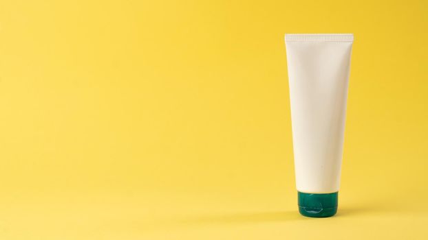 A tube of face or hand cream on a yellow background with space for label and text. High quality photo