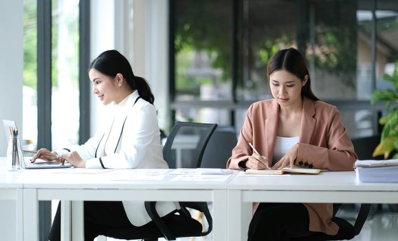 Two Young Asian businesswoman discuss with new startup project Idea presentation, analyze planning and financial statistics and investment market at office..