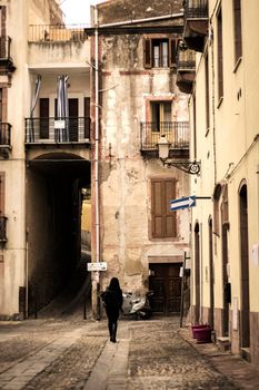 Woman walking in a street in old town in Bosa, a town in Sardegna island in Italy