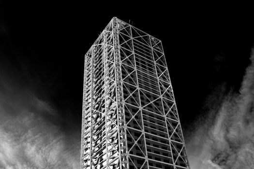 Skyscraper in Barcelona surrounded by clouds and dark sky in the background