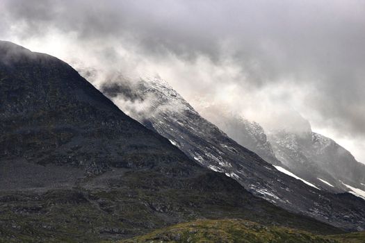 Some snowy mountains aligned under the clouds