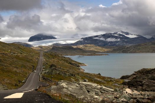 Road in route 55 surrounded by a big lake and snowy mountains and cloudy sky