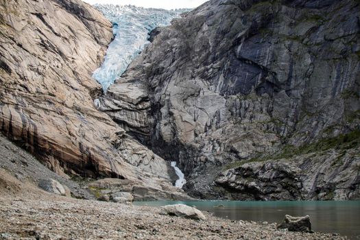 Landscape showing Briksdal glacier in a rocky valley and a lake in long exposure picture