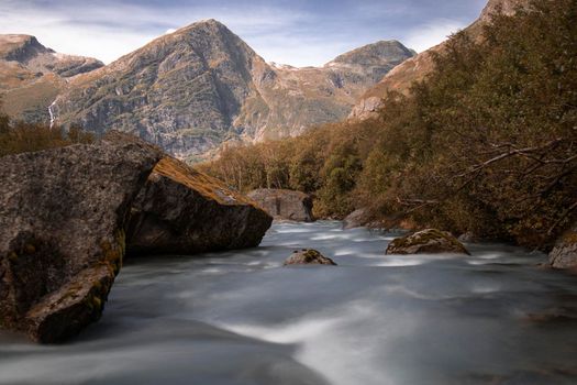 A river in a wild environment and some peaks on the way to Briksdal glacier in Norway