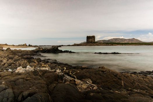 La Pelosa beautiful and tourist rocky beach and tower in Sardegna island in Italy in a long exposure picture