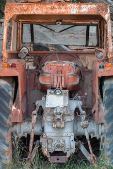 Red decay old tractor abandoned in the countryside