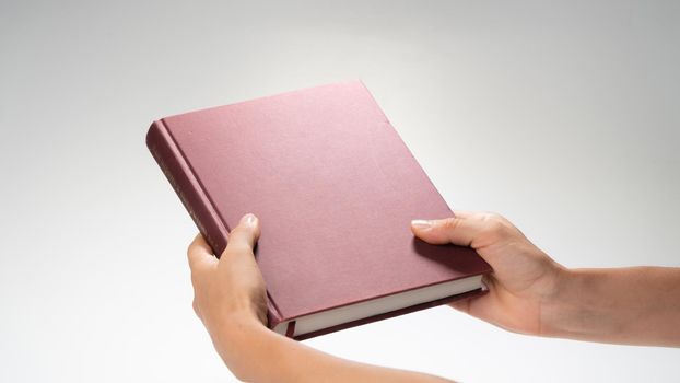 Women's hands holding a closed book, effect under a night lamp. High quality photo
