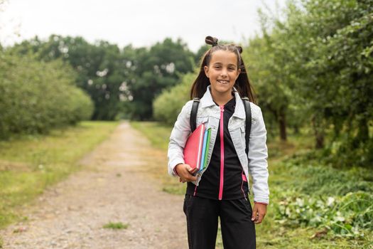 Beautiful little girl with backpack walking ready back to school, fall outdoors, education concept.