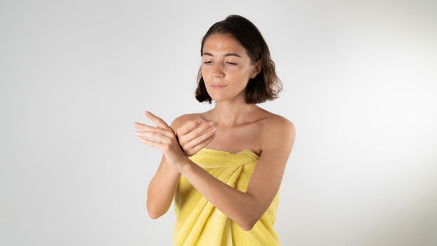 A woman smears her hands with cream after a shower - self-care at home. High quality photo