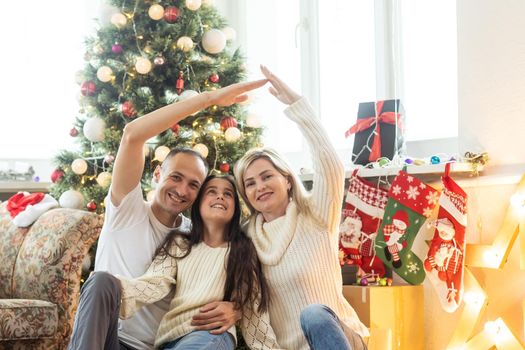 Christmas Family. Happiness. Portrait of dad, mom and daughter sitting at home near the Christmas tree.