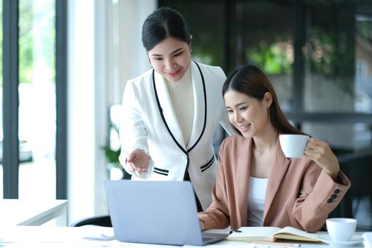 Two Young Asian businesswoman discuss with new startup project Idea presentation, analyze planning and financial statistics and investment market at office..