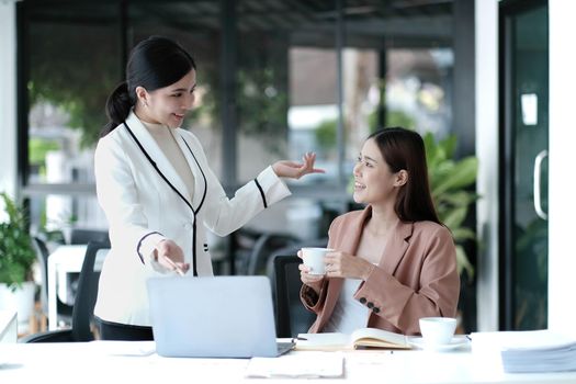 Two Young Asian businesswoman discuss with new startup project Idea presentation, analyze planning and financial statistics and investment market at office..