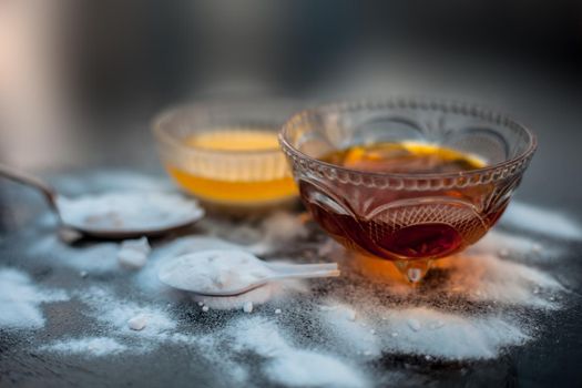 Baking soda face mask in a glass bowl on wooden surface along with baking soda powder and honey for Dark lips.Horizontal shot.