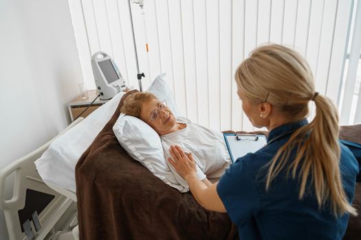 Professional doctor in uniform examines the patient during a visit to hospital ward in clinic