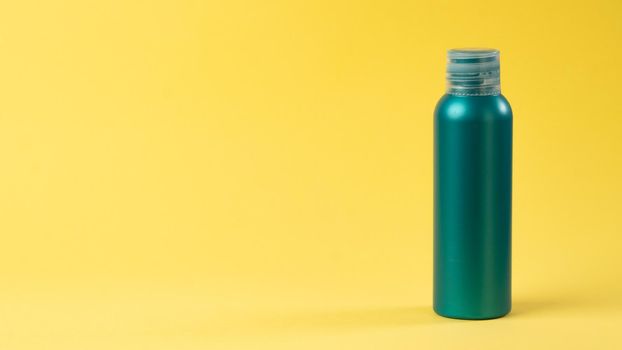 Turquoise bottle with cosmetic on a yellow background with space for text and label. High quality photo