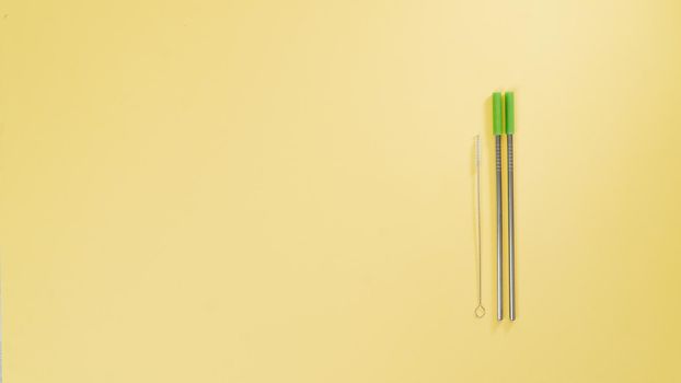 Metal straws for drinks and a brush for cleaning them on a yellow background. High quality photo