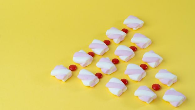 Marshmallows and red candy dragees lined up with a Christmas tree. High quality photo