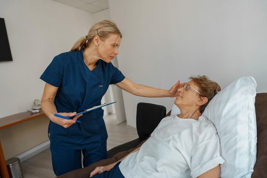 Professional doctor in uniform examines the patient during a visit to hospital ward in clinic