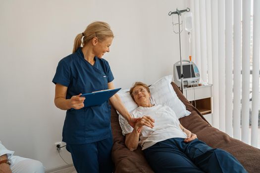 Nurse supporting a sick patient before medical procedures in a hospital room. High quality photo