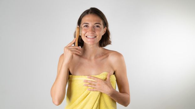 Woman with massage brush does face lift at home after shower. High quality photo