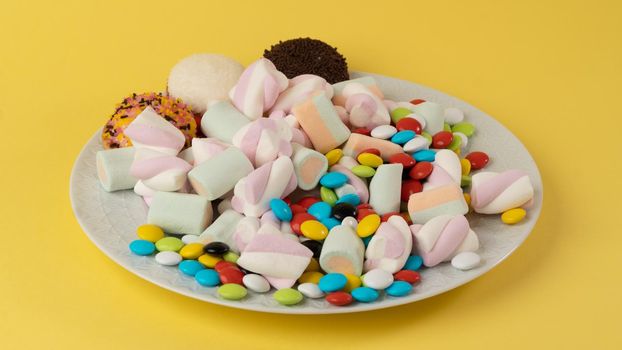 Plate with sweets on a yellow background. High quality photo