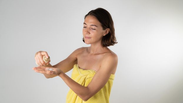 A woman squeezes the cream serum on the palm of her hand after a shower - body and face care at home. High quality photo